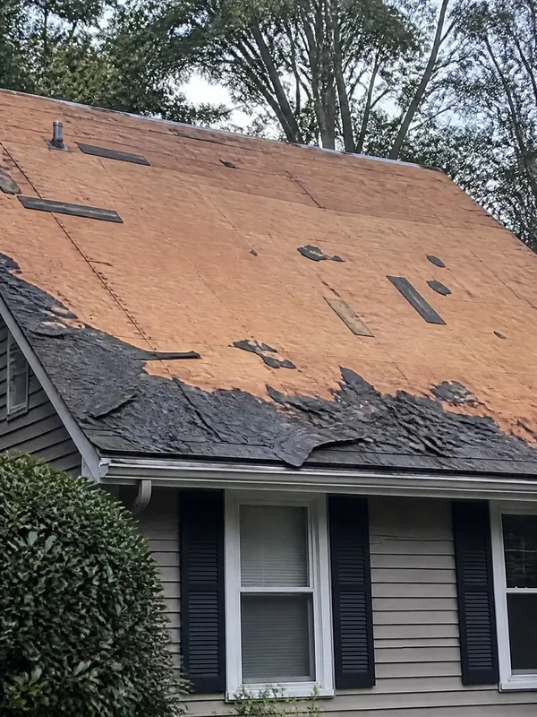 Roof tear-off in progress, old shingles half removed